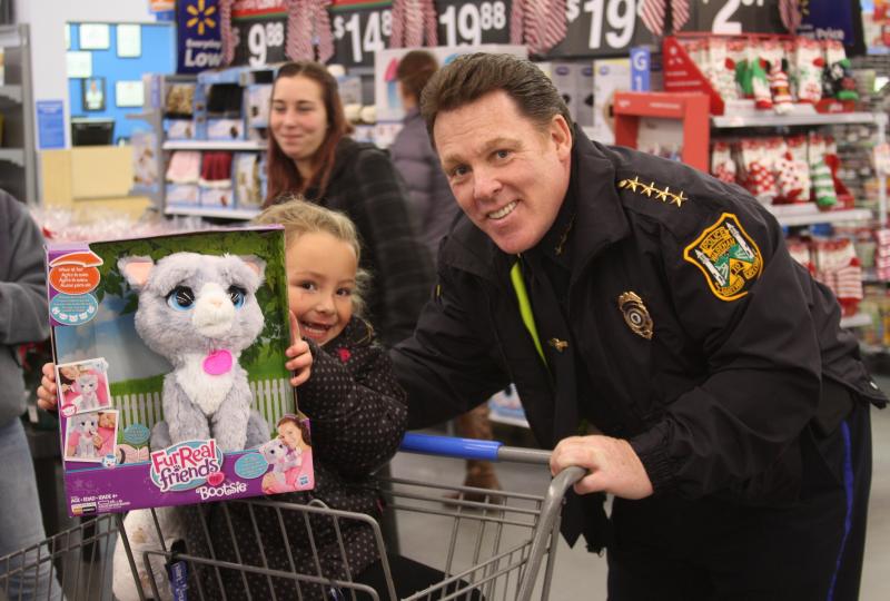 Amyra Taggert beams alongside Wareham Police Chief Kevin Walsh before buying gifts during "Shop With a Cop" on Wednesday night in Walmart. BY MATTHEW BERNAT